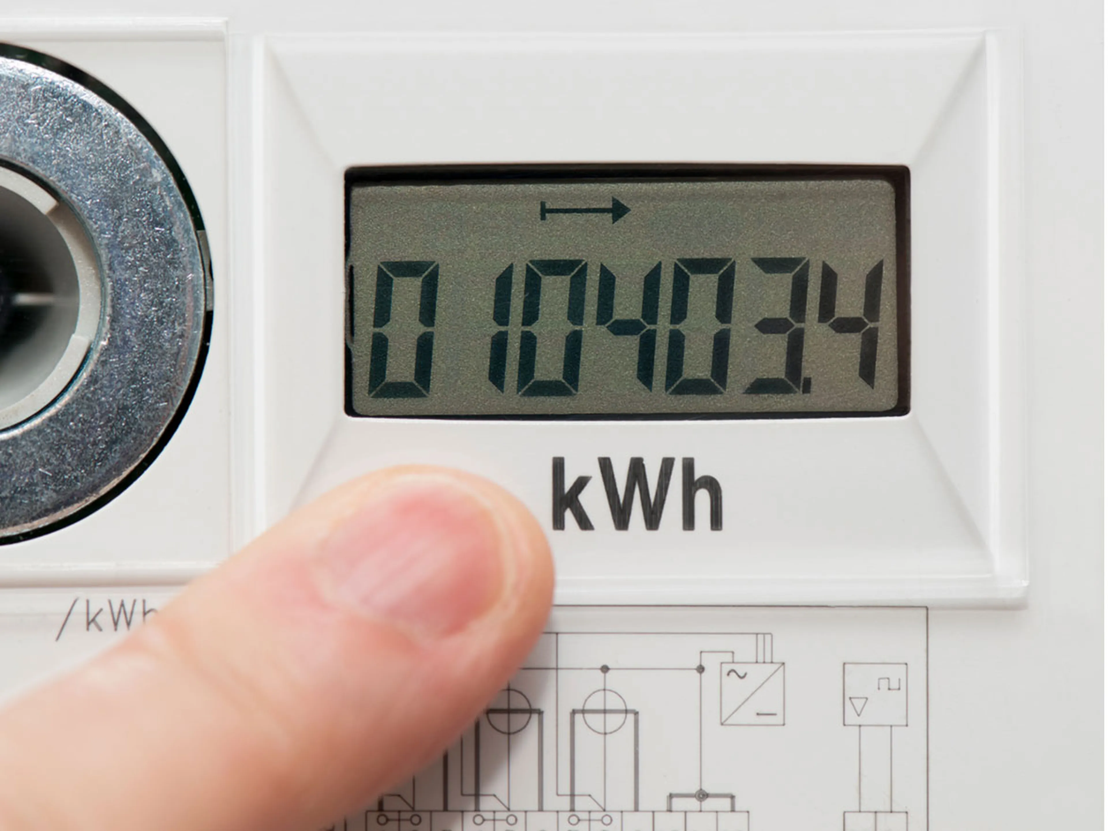 Jemand zeigt mit dem Finger auf die Verbrauchsanzeige eines digitalen Stromzählers: Die Anzeige zeigt 10403 kWh an.