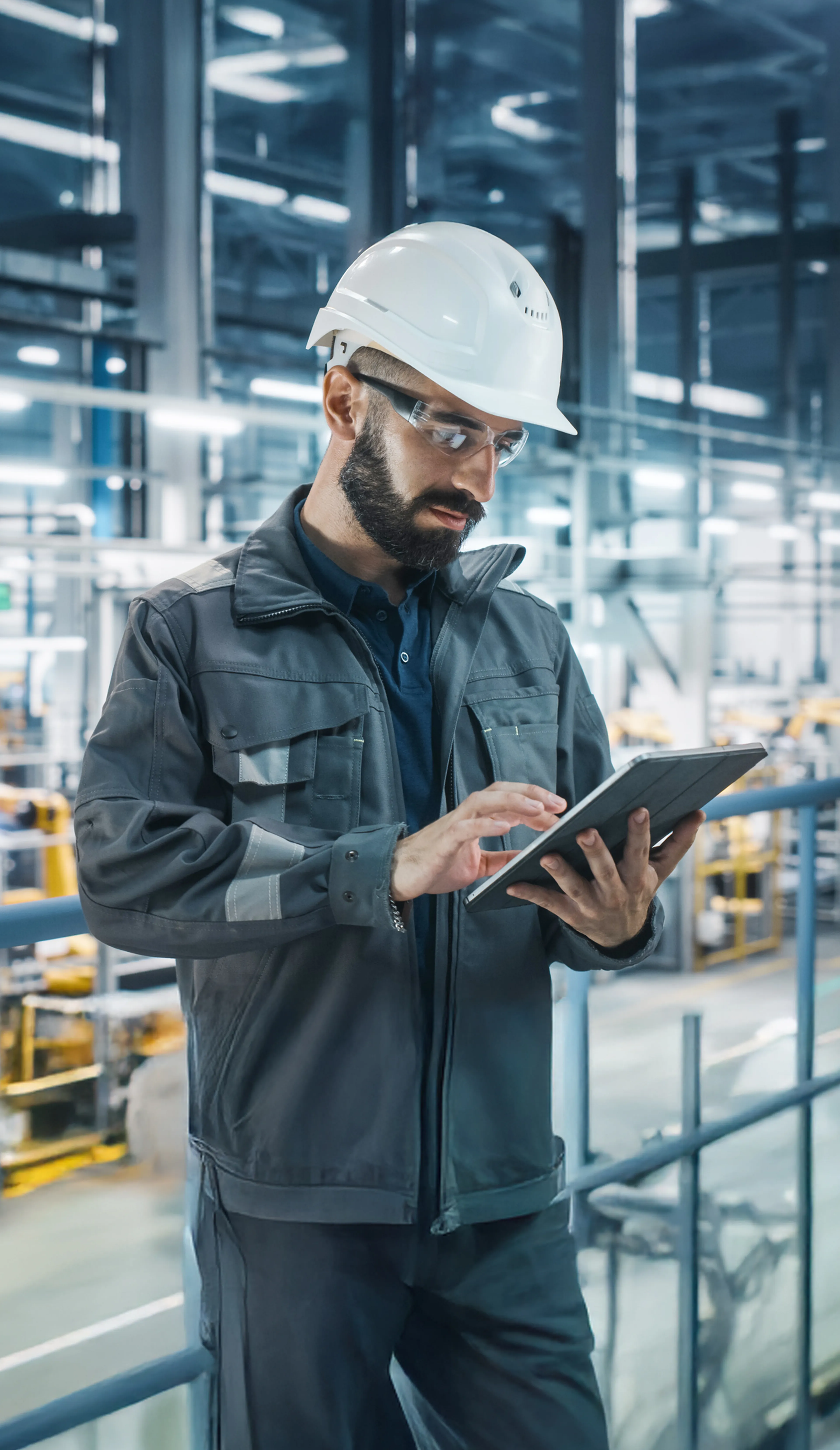 Industriearbeiter mit Schutzhelm und Tablet in moderner Fabrikhalle