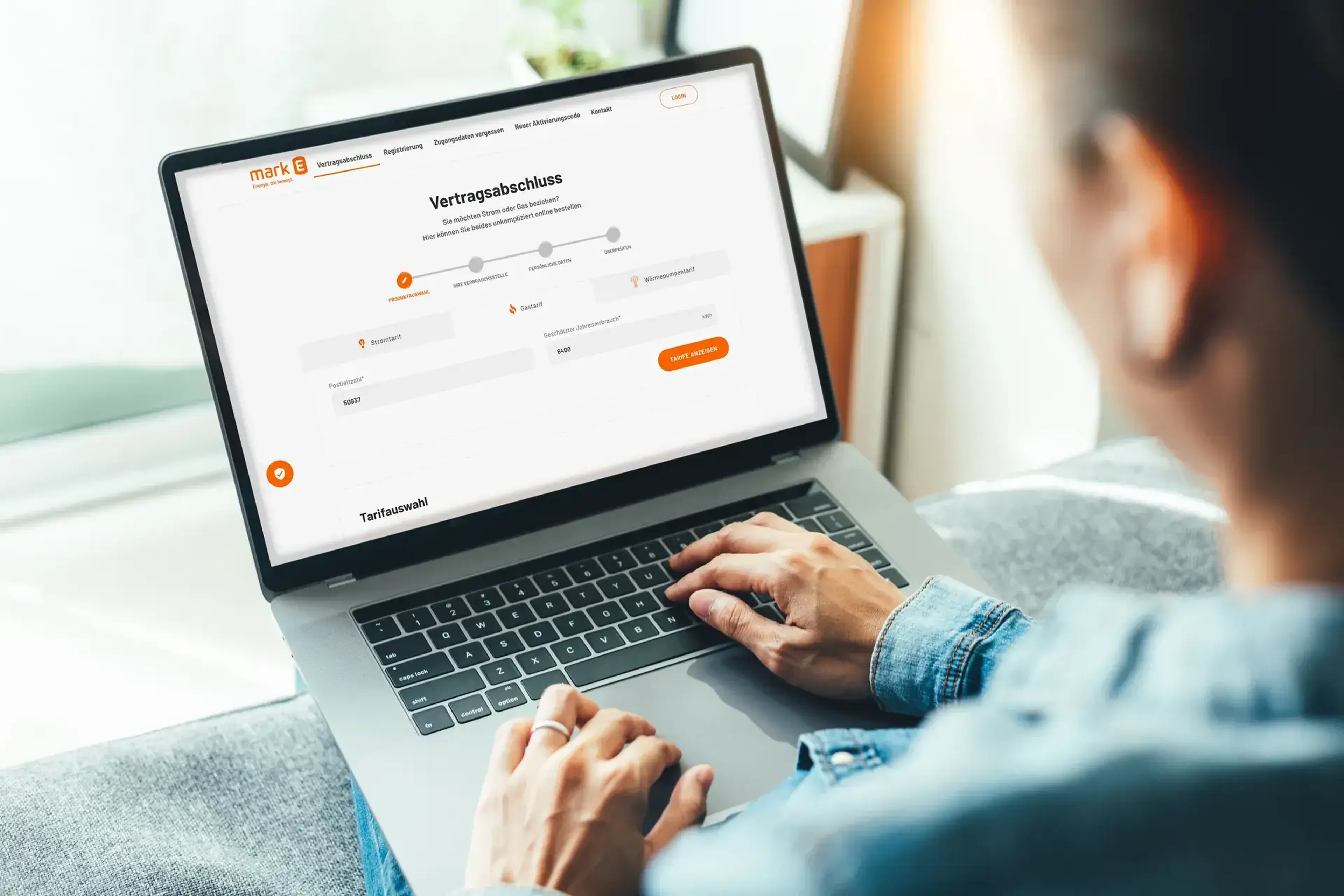 Eine Person sitzt auf einem Sofa und benutzt einen Laptop, auf dessen Bildschirm ein Vertragsformular angezeigt wird