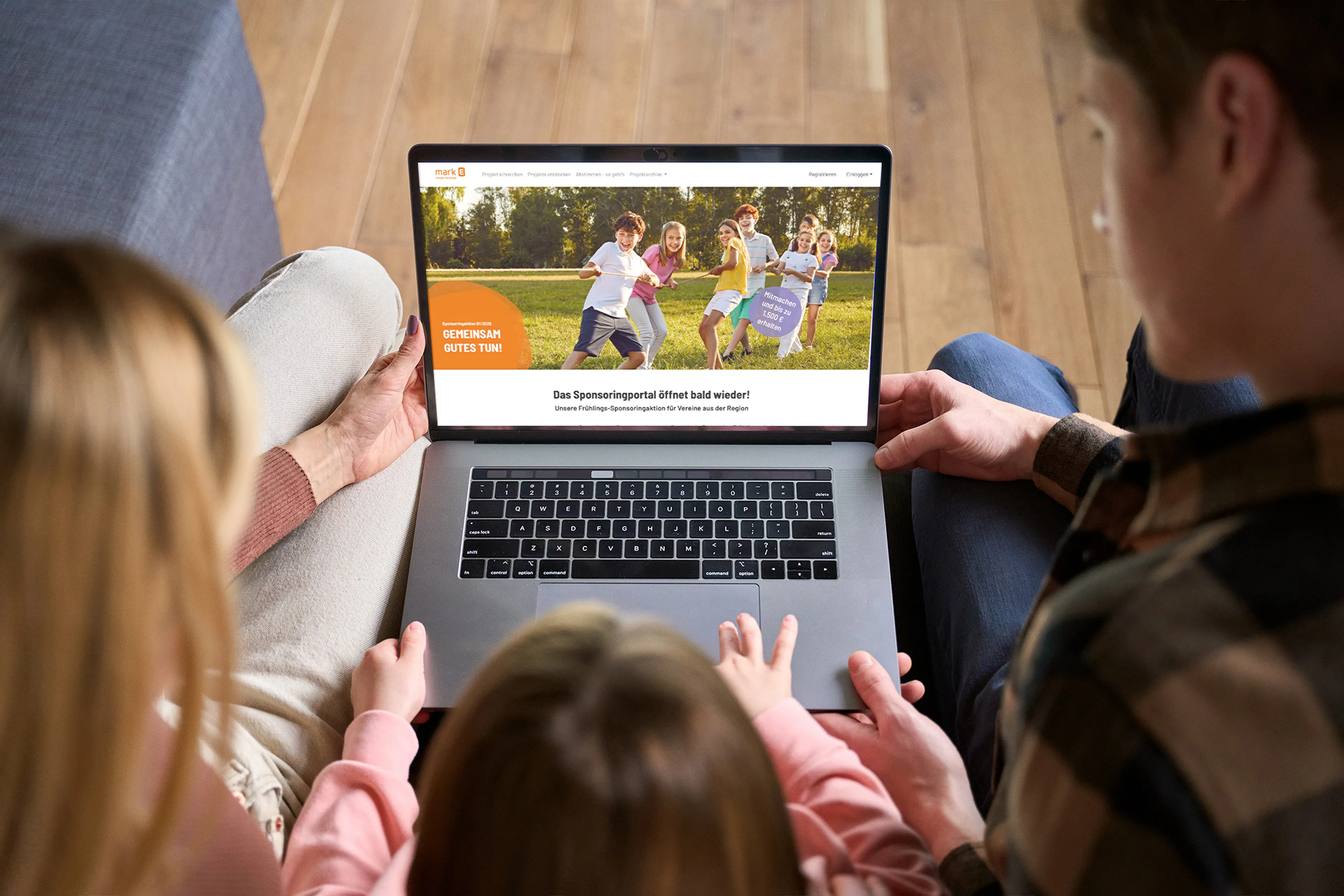 Eine Frau, ein Mann und ein Kind sitzen auf dem Sofa und schauen sich die Sponsoring Seite auf dem Laptop an.