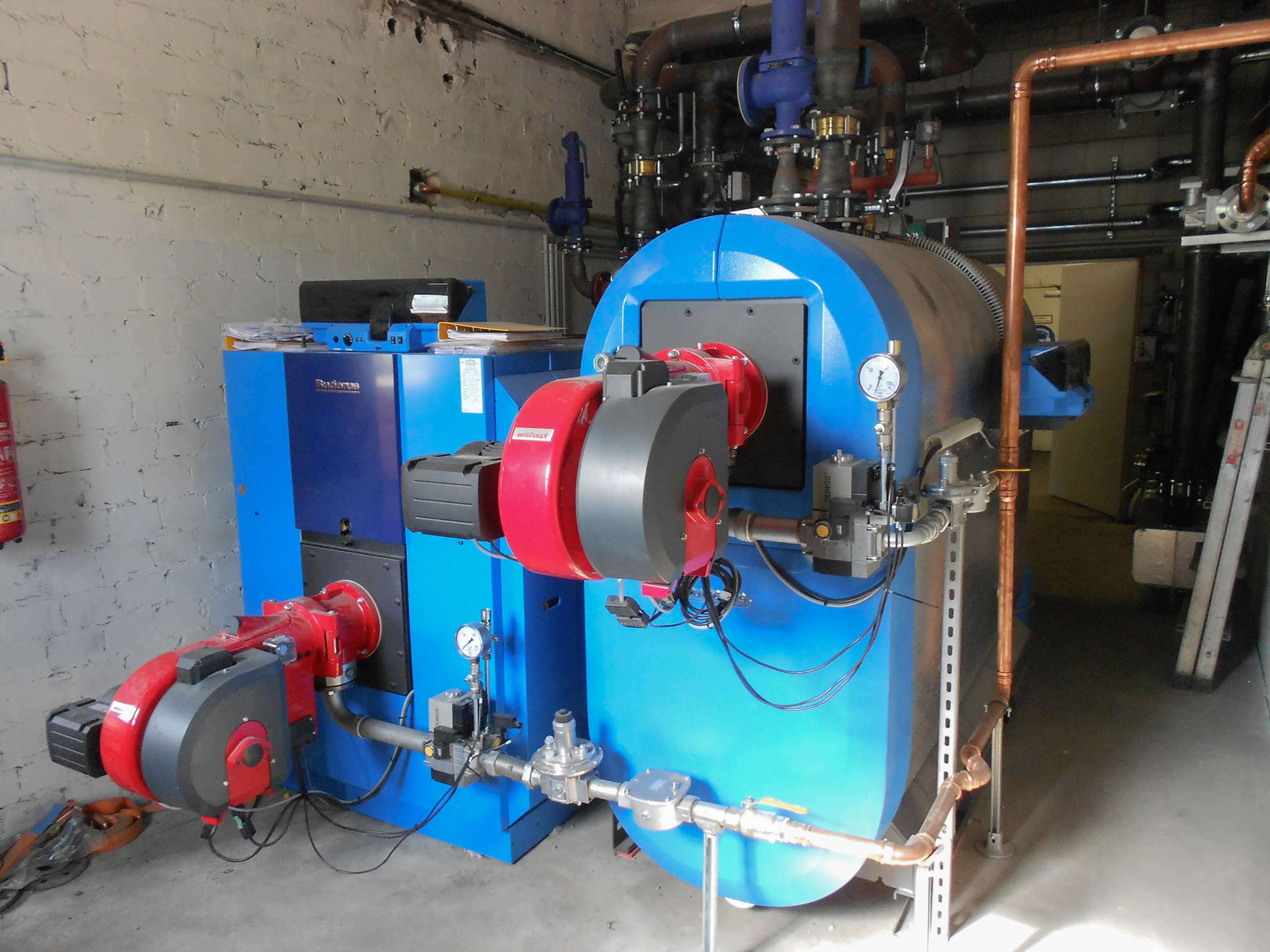 Großer Industriekessel in einem Heizraum mit blauer Verkleidung und roten Brennern