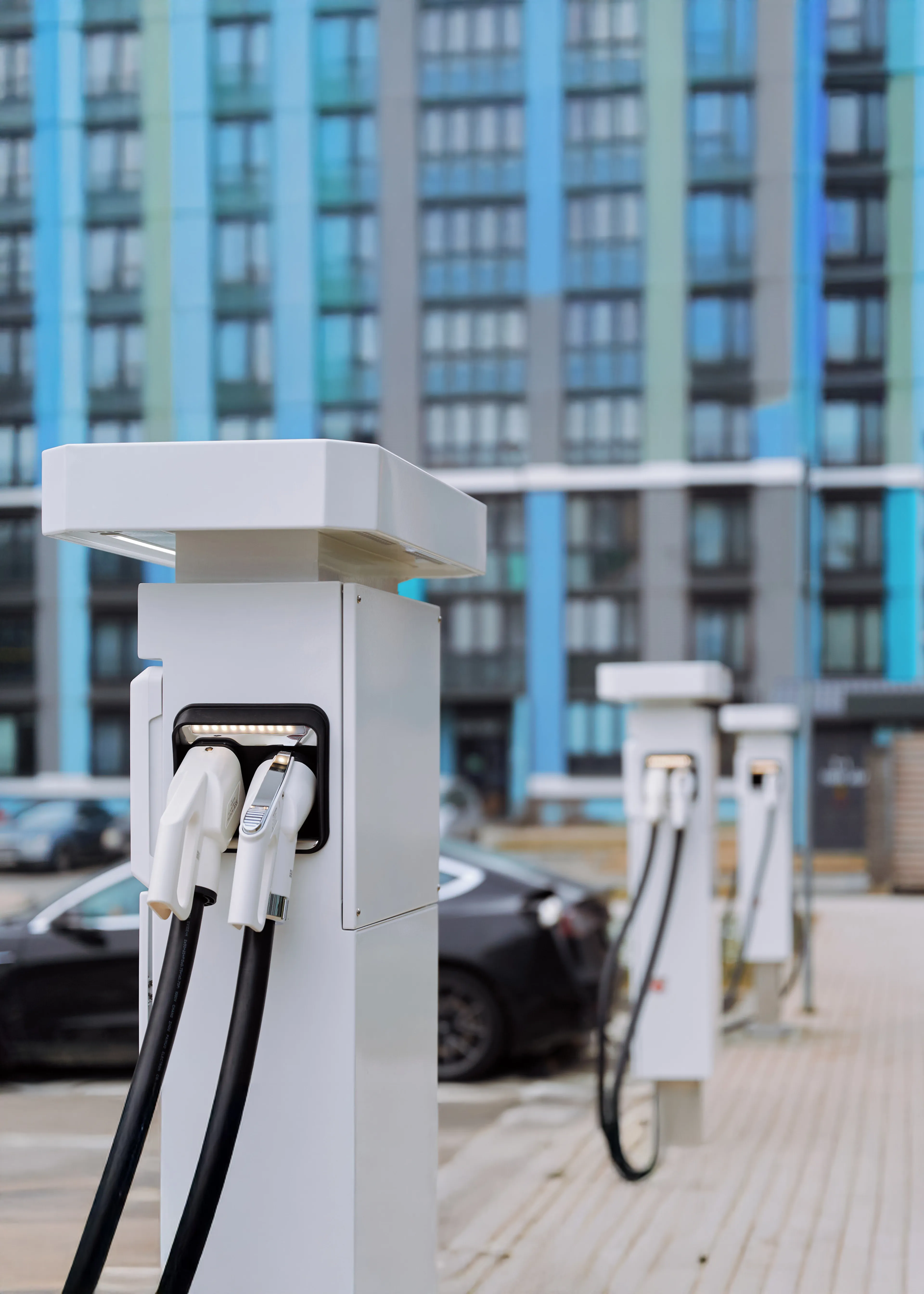Mehrere halböffentliche Ladestation vor einem großen Gebäudekomplex.