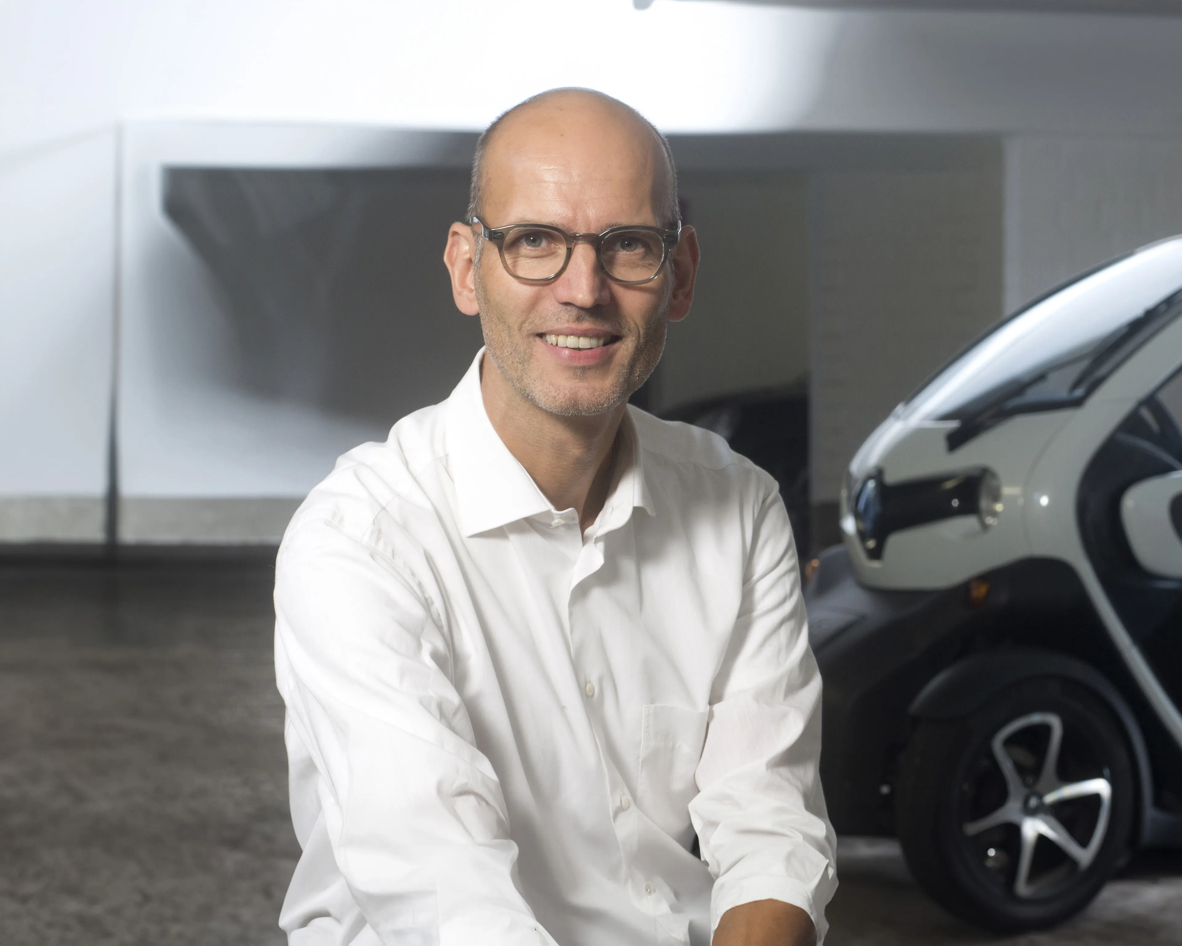 Dr. Armin Windel vor seinem Elektroauto im Parkhaus
