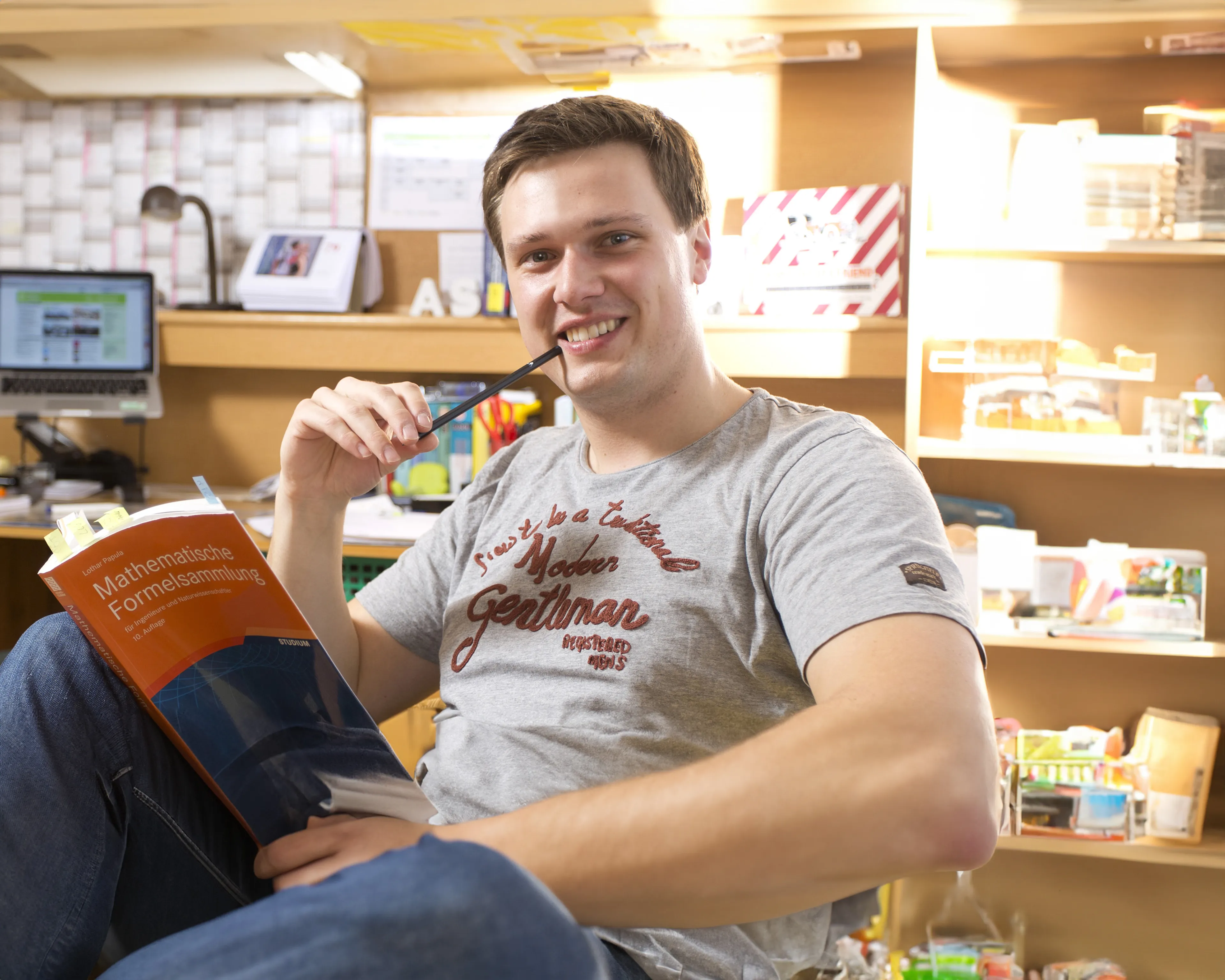 Sascha Gerber beim Lernen an seinem Schreibtisch mit Buch und Laptop