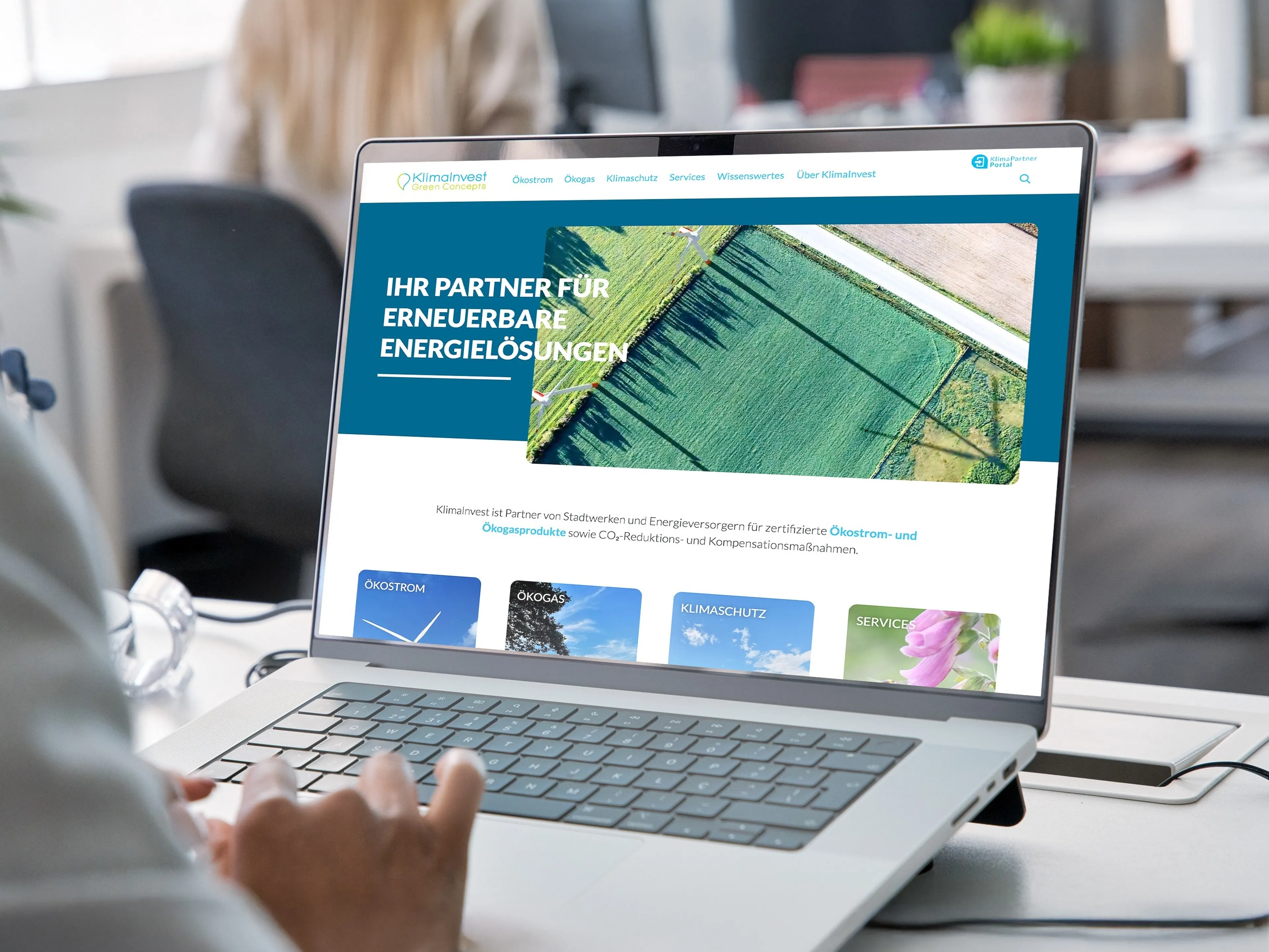 Person ist am laptop. Auf dem Bildschirm ist die Homepage von Klimainvest, dem Partner für erneuerbare Energielösungen zu sehen.