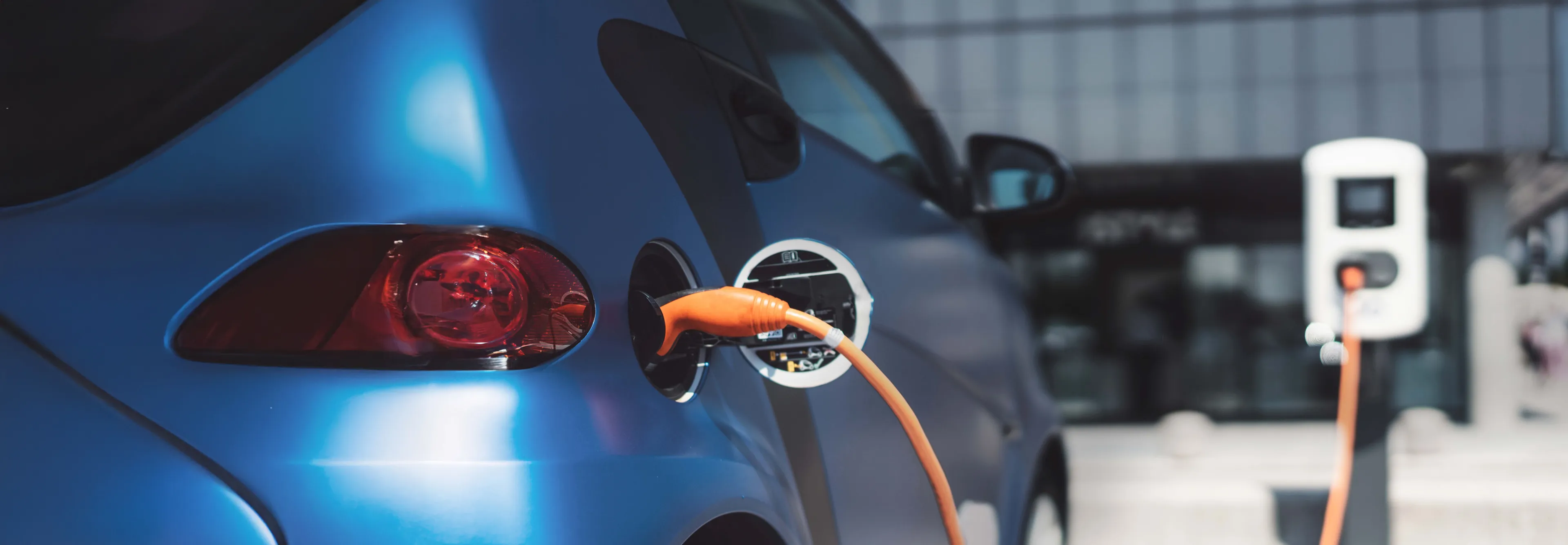 Blaues Auto ist an eine Wallbox angeschlossen und lädt