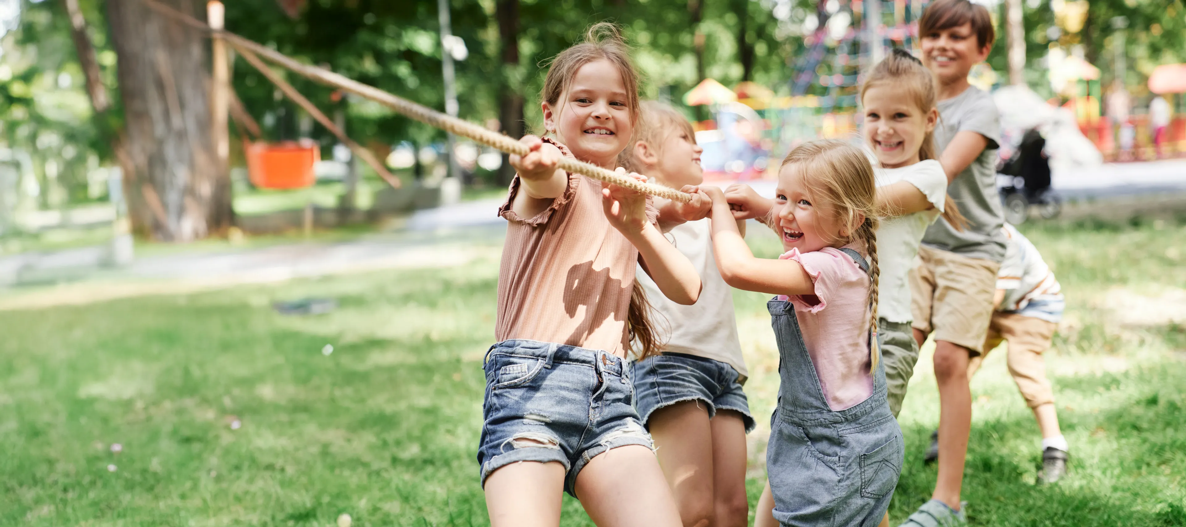 Sechs Kinder ziehen an einem Seil und lachen dabei.