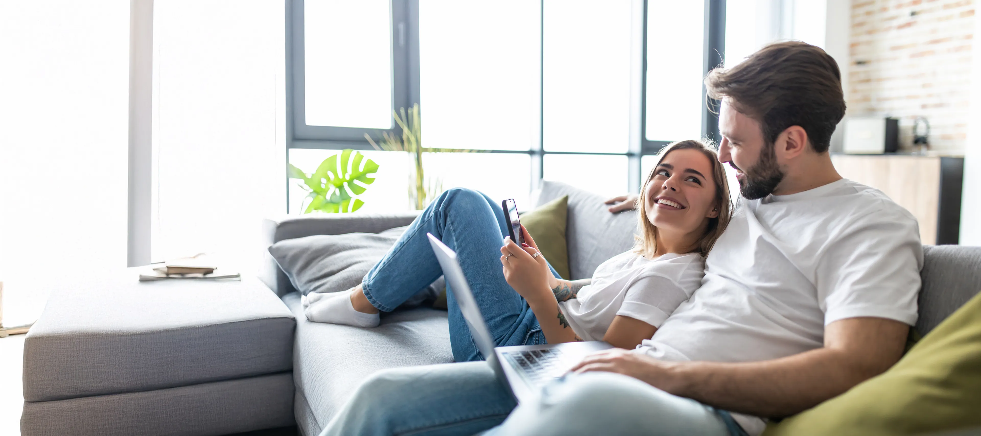 Paar sitzt auf Sofa und lächelt sich an