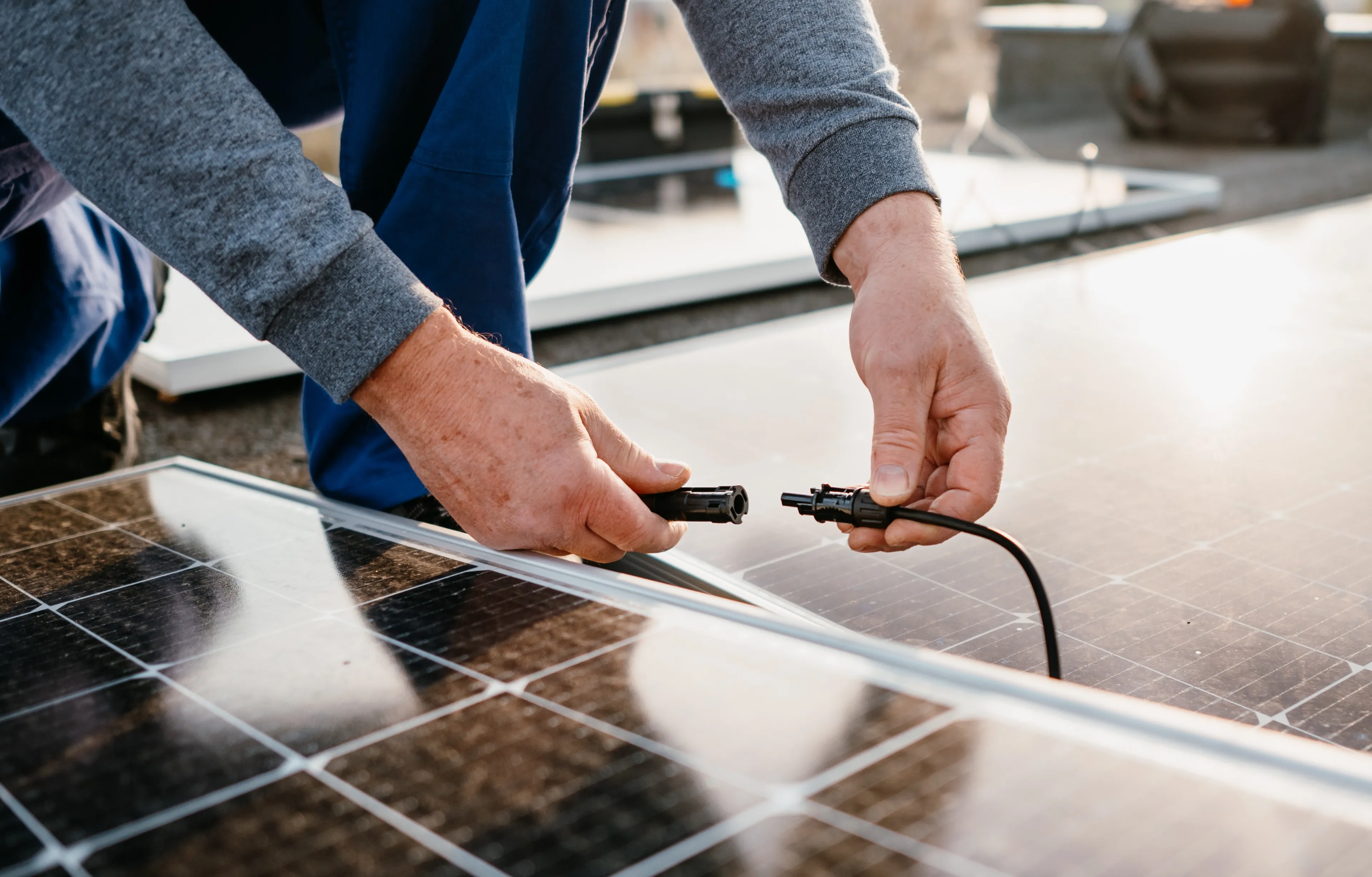 Handwerker verbindet Solarpanels auf einem Dach – Photovoltaik Mieterstrom für moderne Wohnkonzepte mit Mark-E.