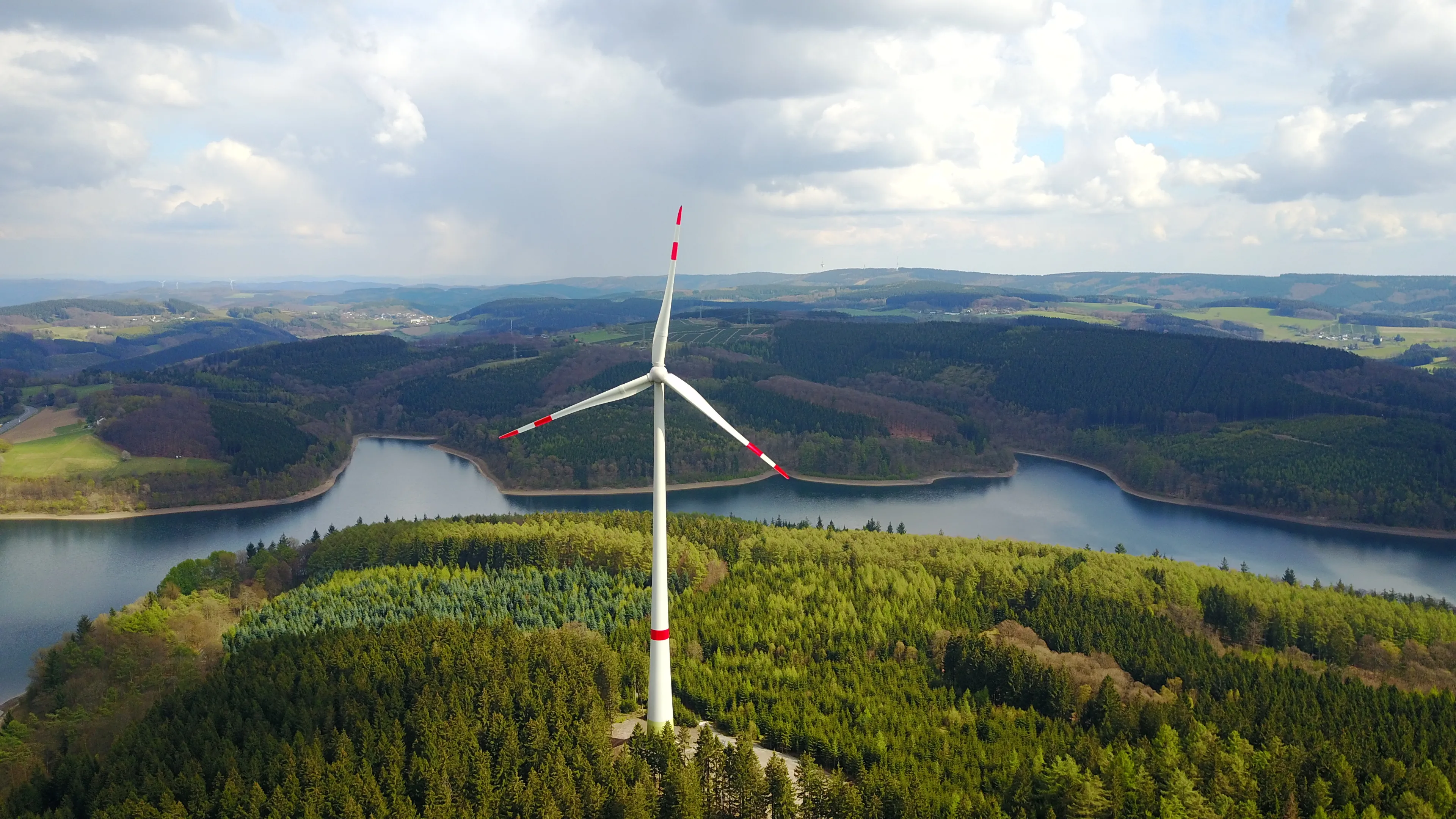 Windrad im Wald an einem See – erneuerbare Energie mit Mark-E