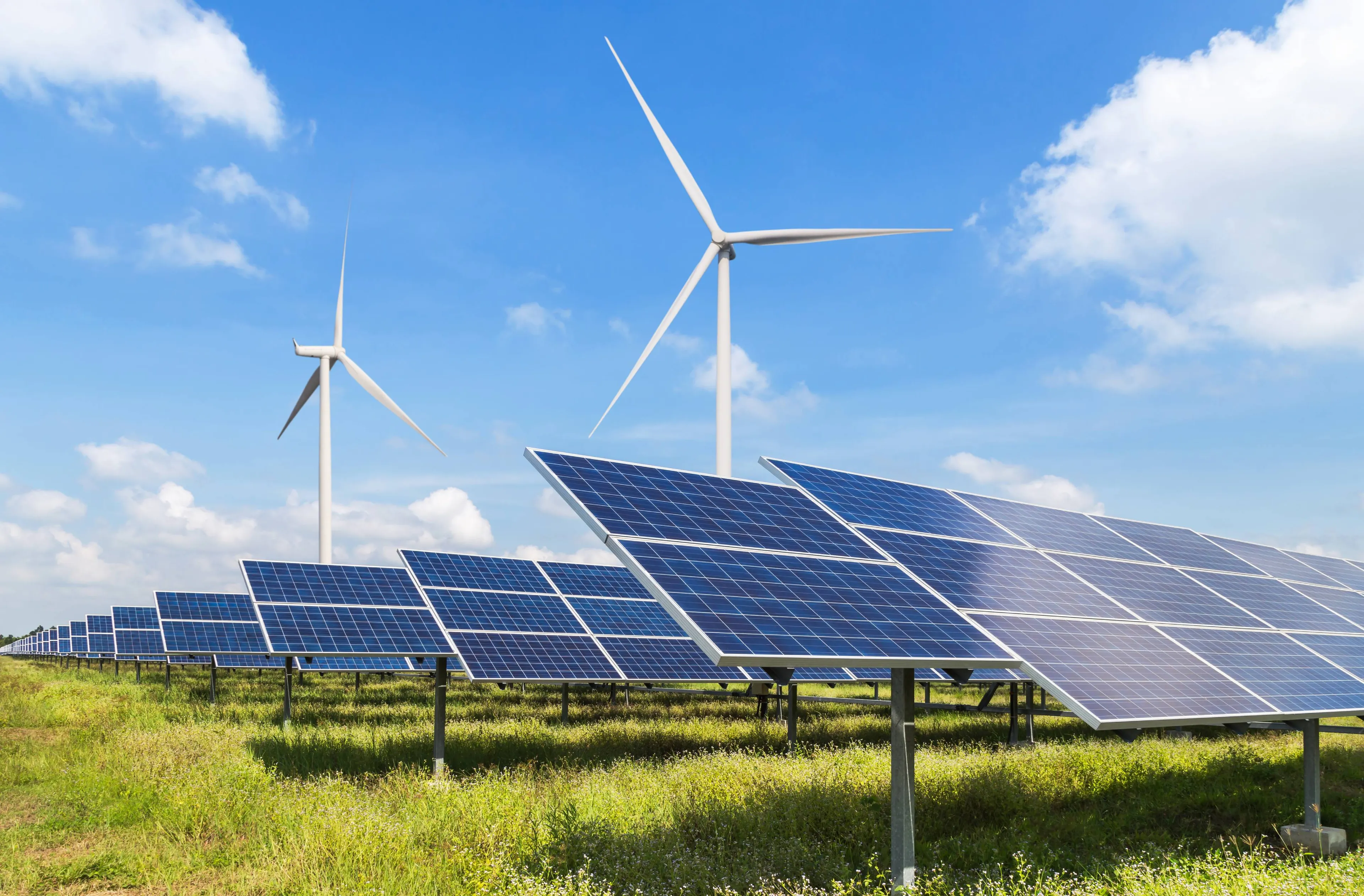 Solaranlagen und Windräder auf einem Feld zur Erzeugung erneuerbarer Energie bei Sonnenschein.