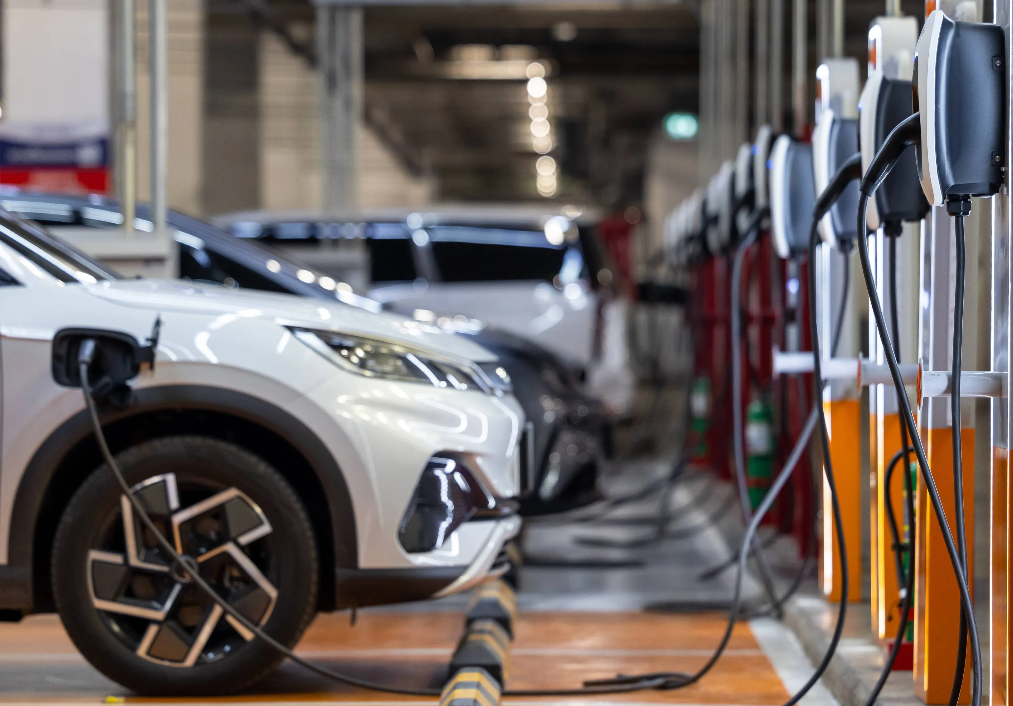Elektroautos werden an einer Reihe von Wallboxen in einer modernen Tiefgarage geladen.
