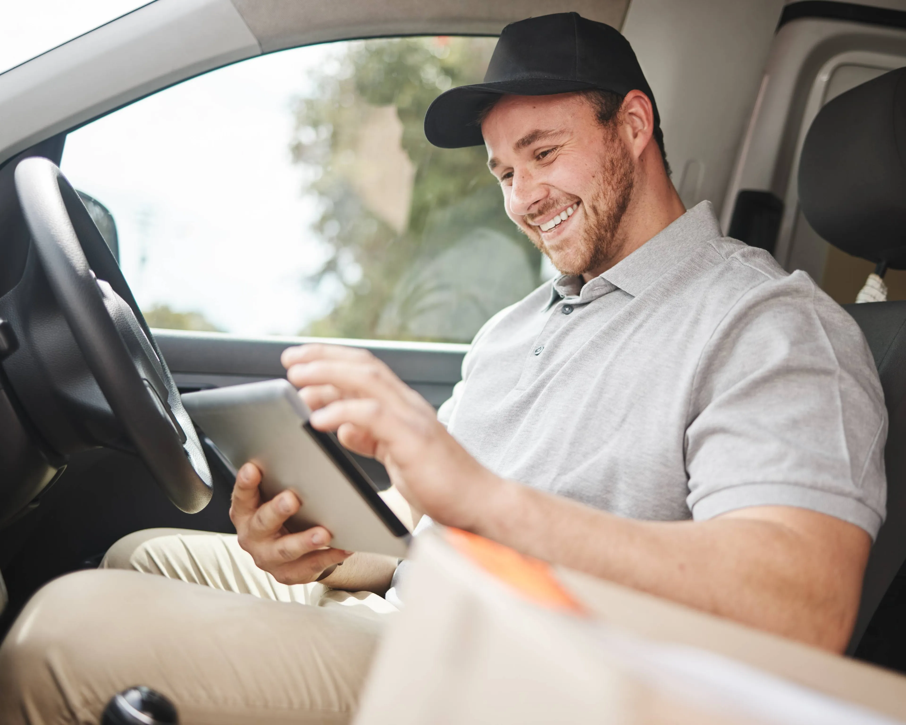 Lieferfahrer im E-Fahrzeug nutzt ein Tablet – smarte E-Mobilitätslösungen für Unternehmen von Mark-E.