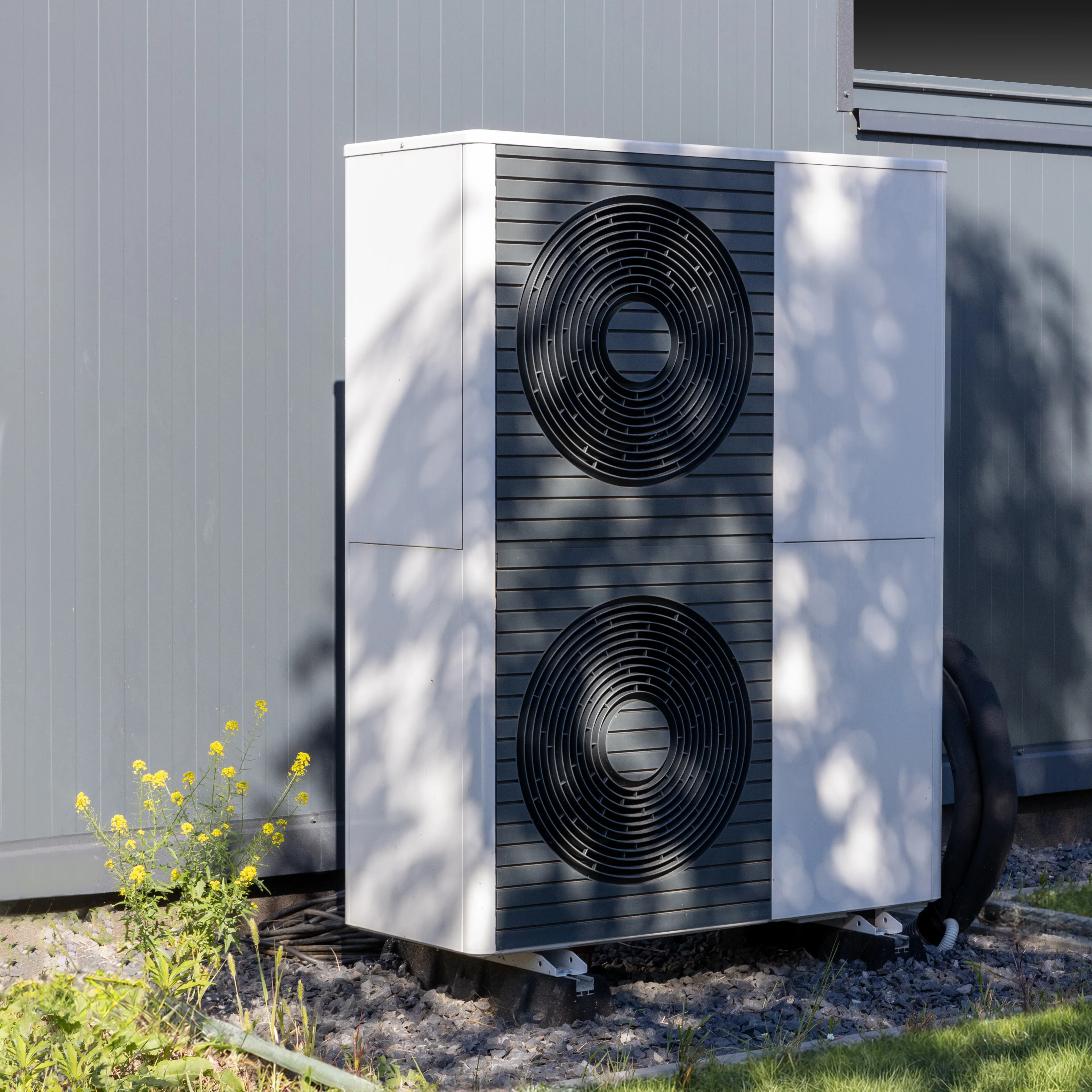 Freistehende moderne Wärmepumpe an der Hauswand bei Tageslicht