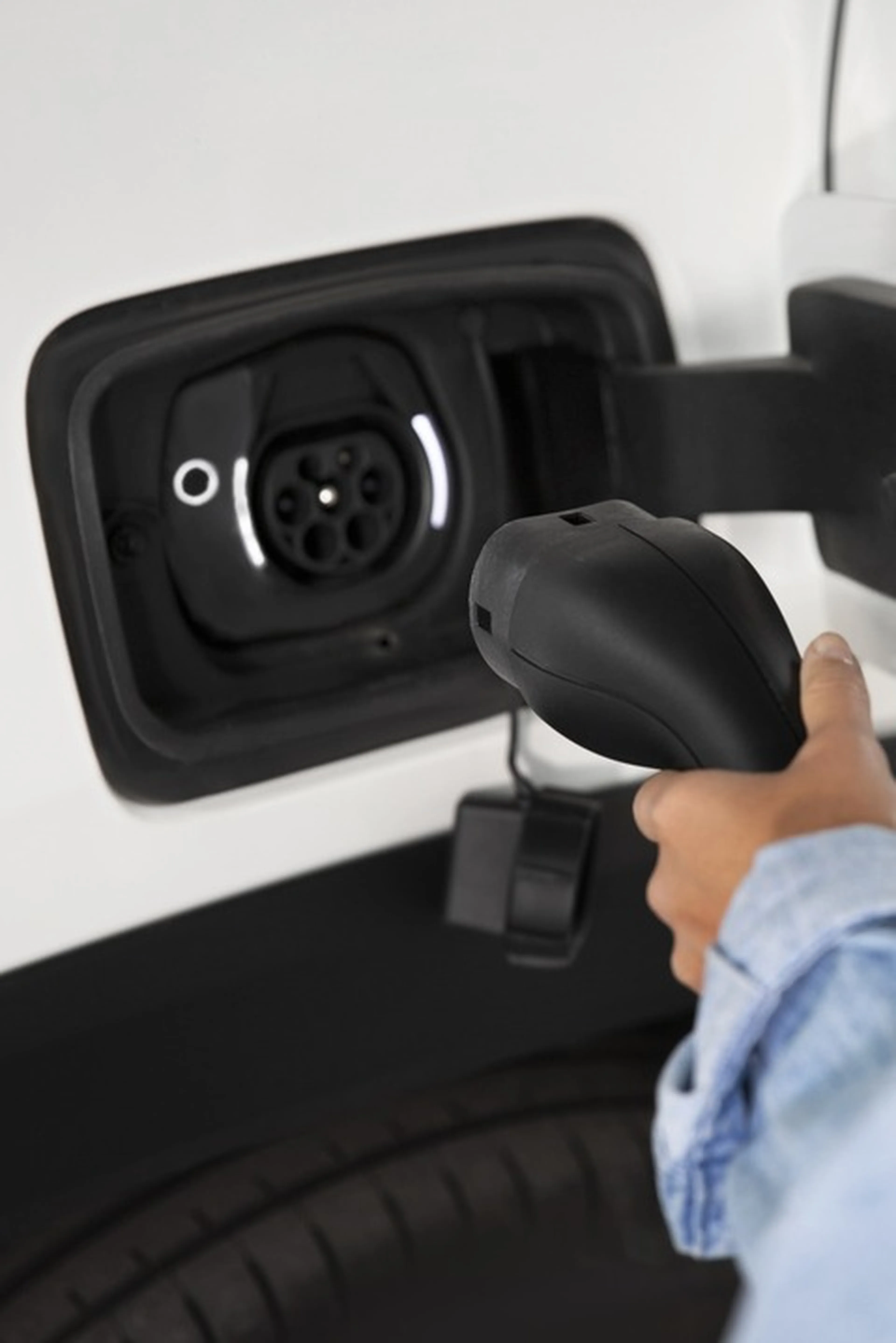 Person steckt Ladekabel in E-Auto