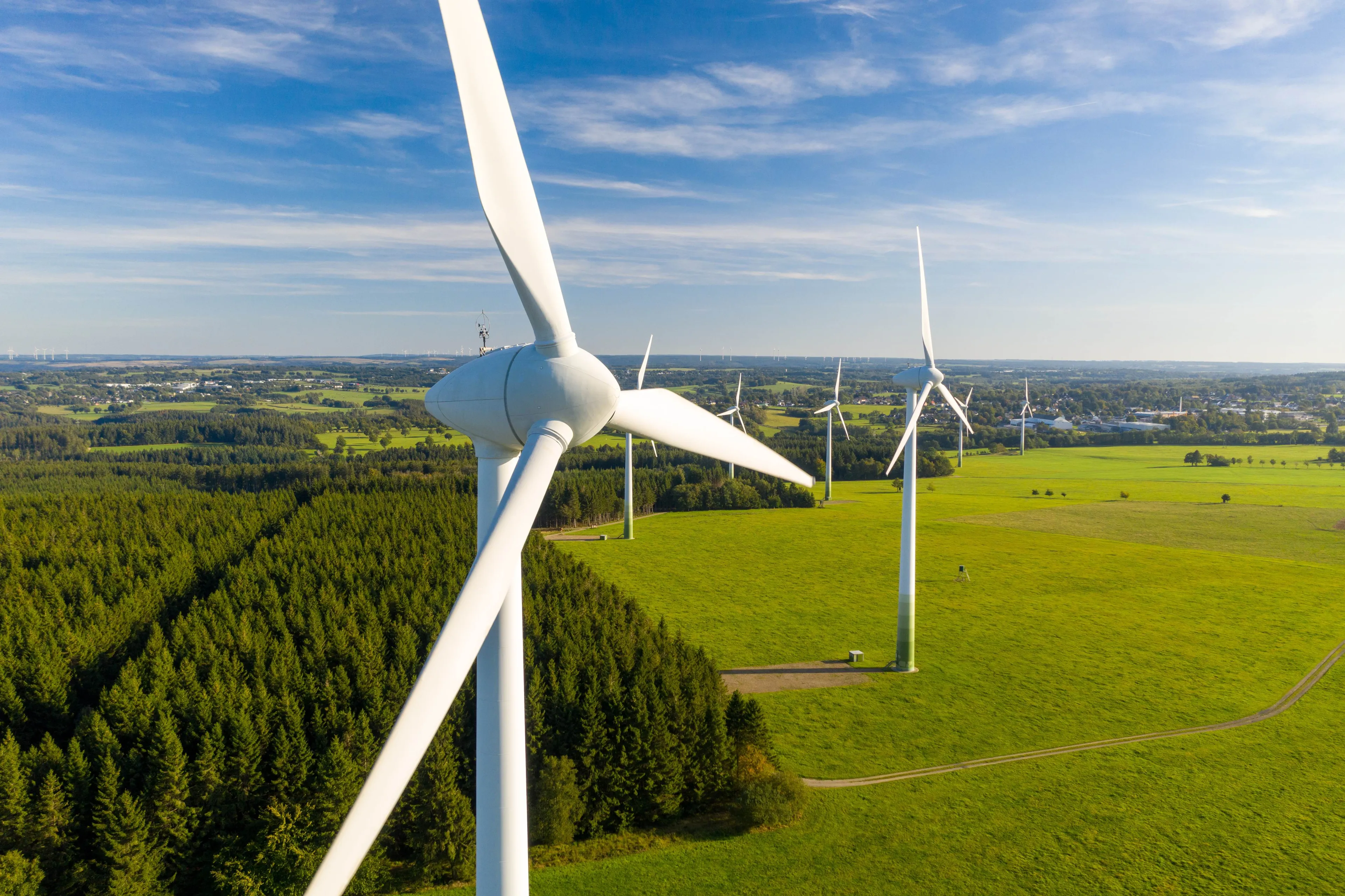 Windkraftanlagen auf einem grünen Feld bei Sonnenschein