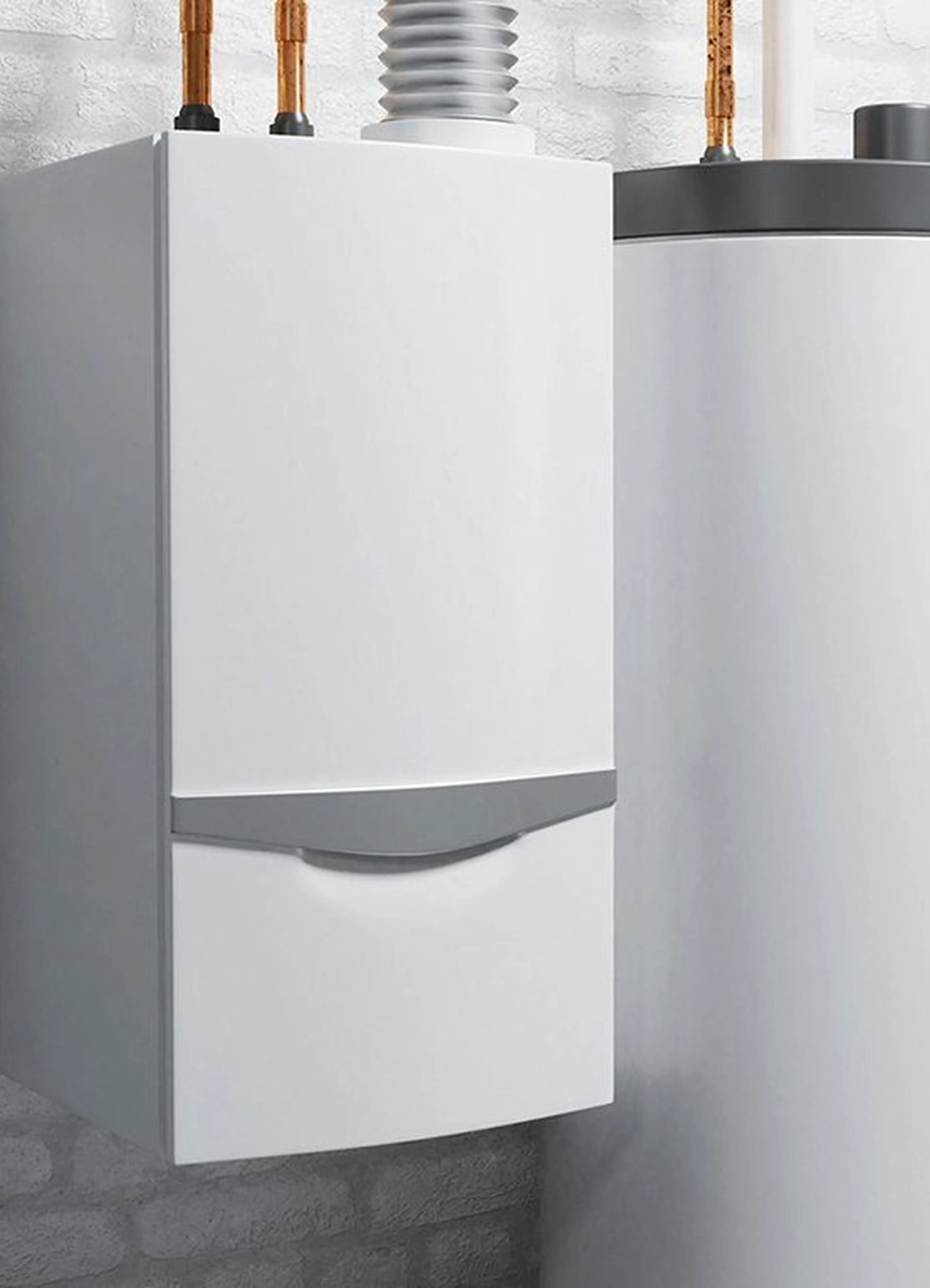 Weißer Heizkessel und zylindrischer Warmwasserbereiter vor einer weißen Backsteinwand, oben durch Rohre verbunden.