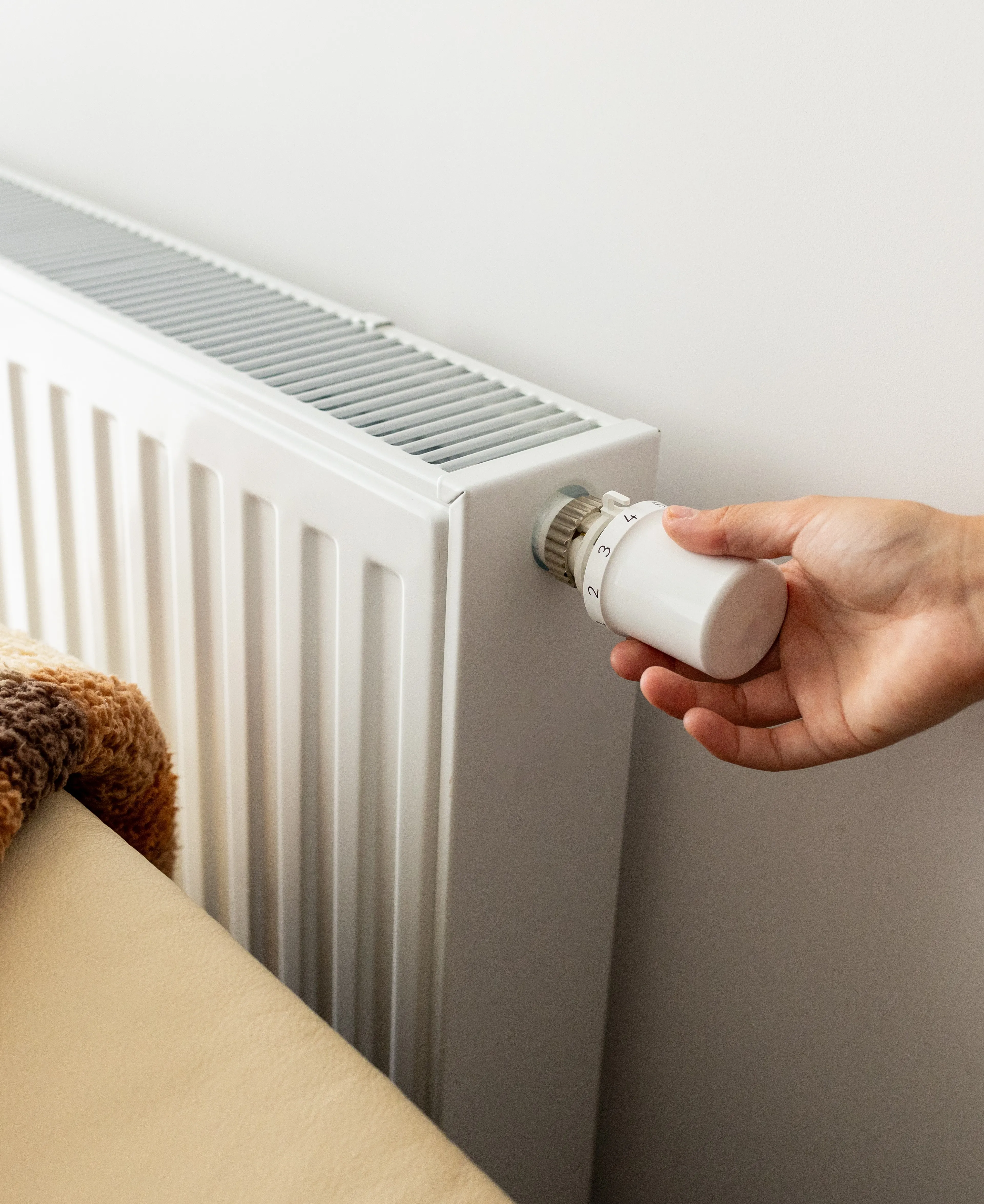 Hand dreht an einem Heizungsregler – komfortabel und günstig heizen mit Fix Gas von Mark-E.