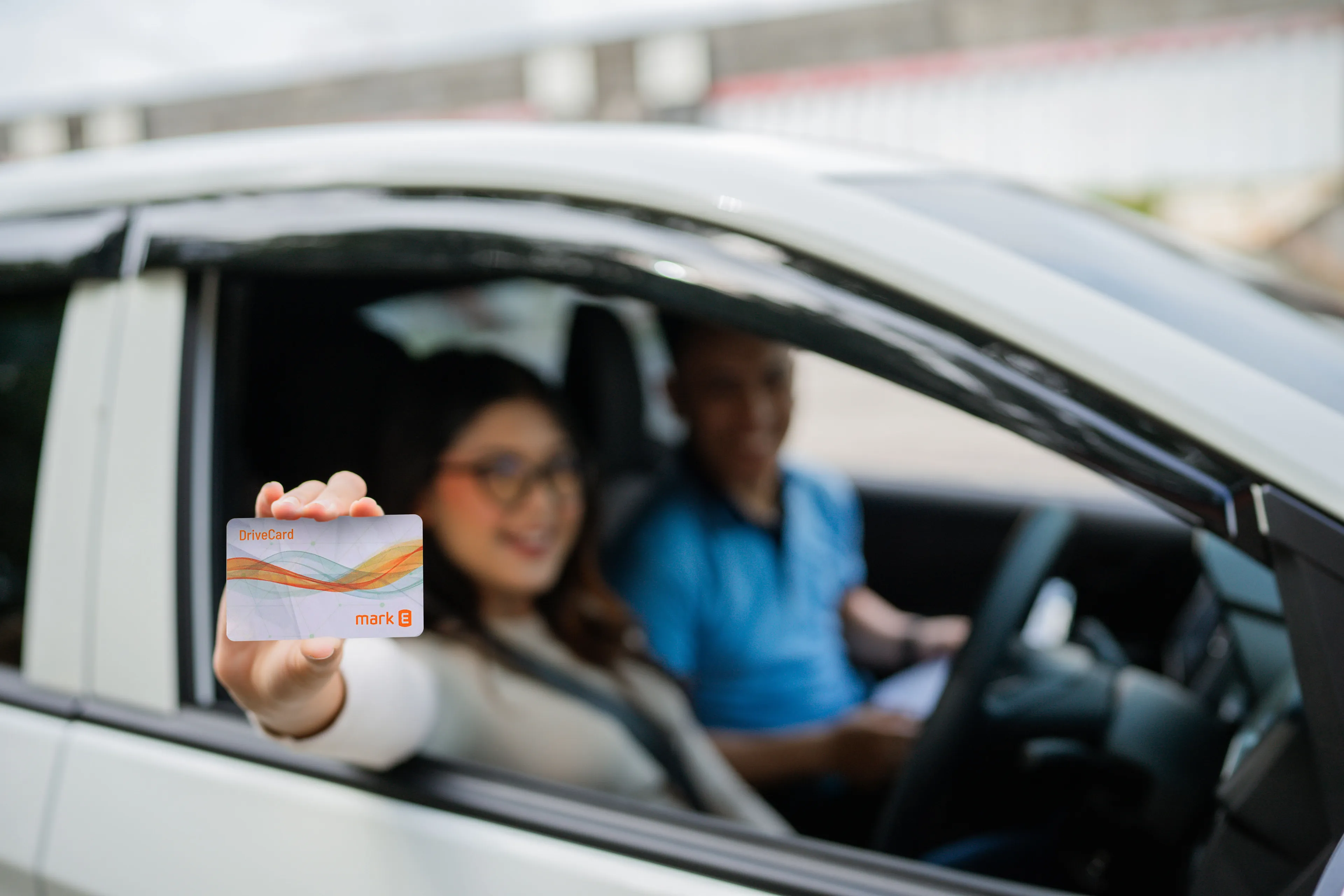 Frau hält DriveCard aus dem Elektroauto