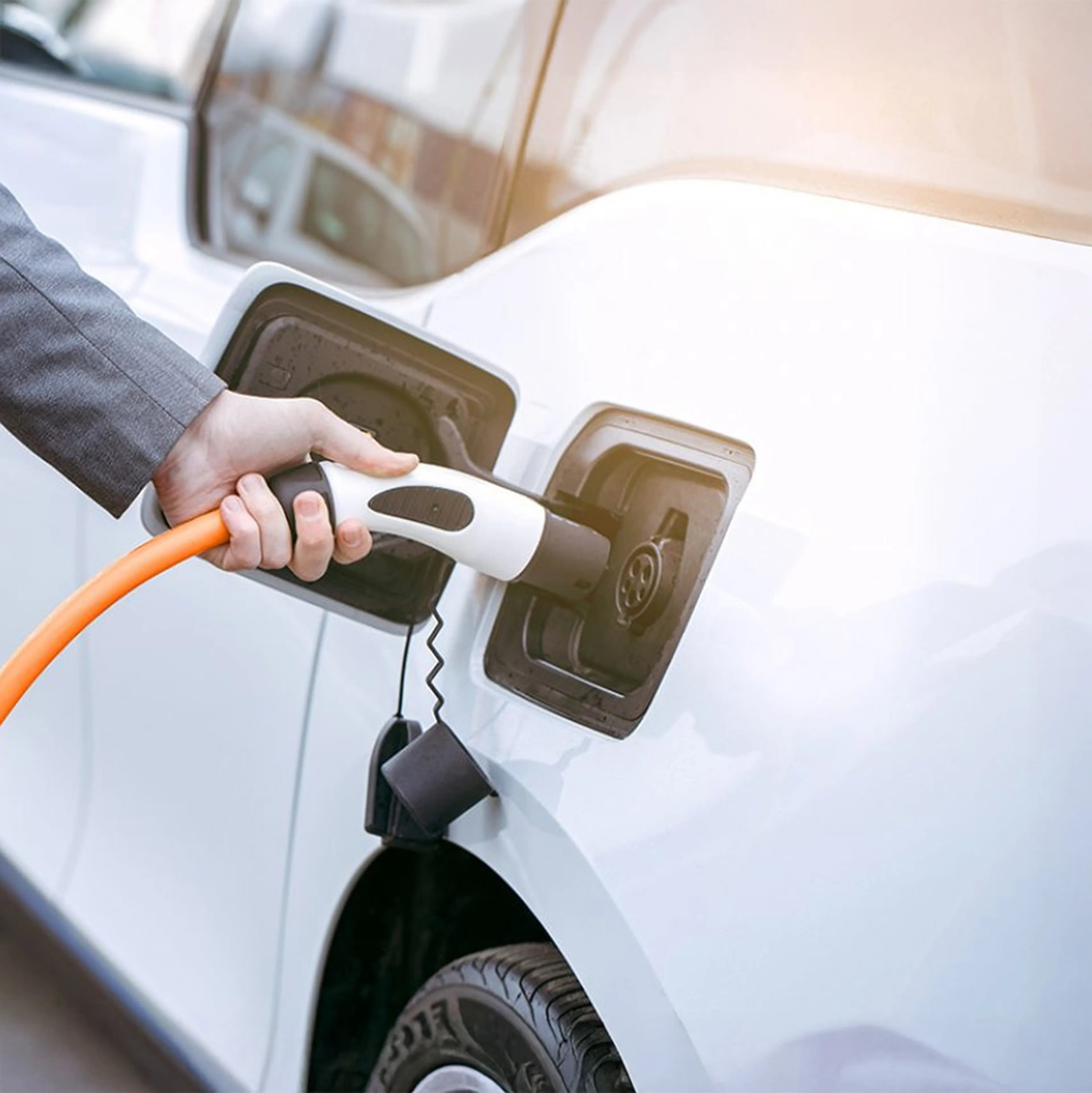 Elektroauto wird per orangem Kabel an einer Ladestation aufgeladen.